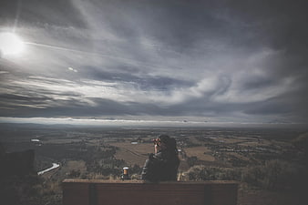Person sitting on bench overlooking vast valley landscape