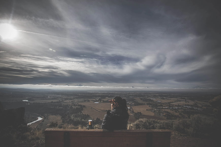 Person sitting on bench overlooking vast valley landscape