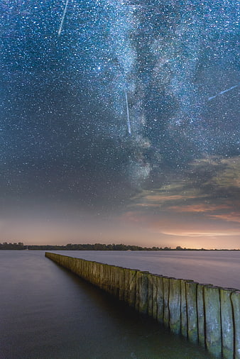Perseid Meteor Shower over Wooden Breakwater at Night
