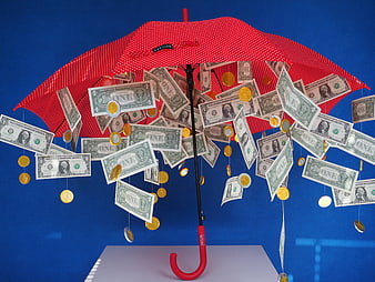 Red Umbrella Protecting Dollar Bills and Coins Against Blue Background