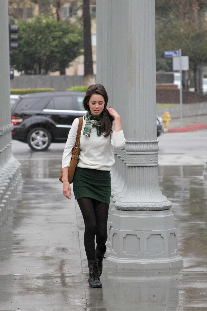 Woman Walking on Wet City Sidewalk in Rain