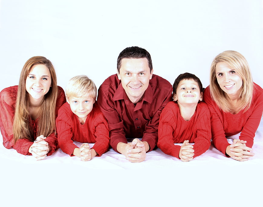 Happy family of five lying on white background in red clothes