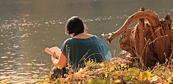 Woman reading a book by a lake in autumn