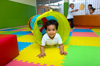Happy toddler crawling through colorful play tunnel