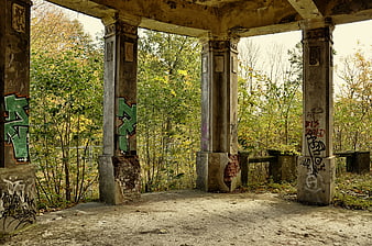 Abandoned concrete pavilion with graffiti in autumn forest