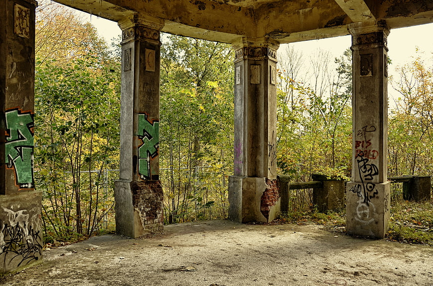 Abandoned concrete pavilion with graffiti in autumn forest