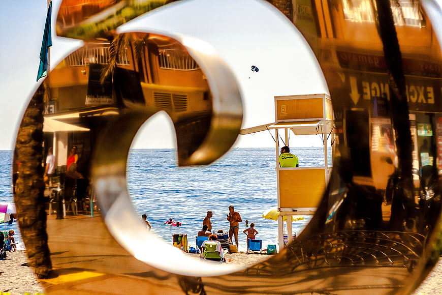 Beach scene viewed through reflective metal sculpture