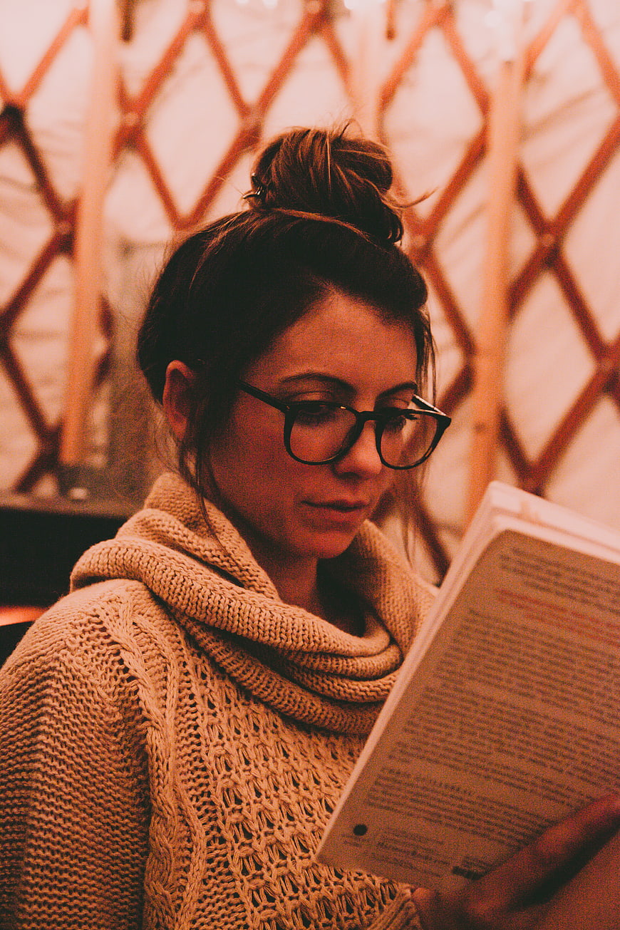 Woman with Glasses Reading Book in Cozy Knit Sweater