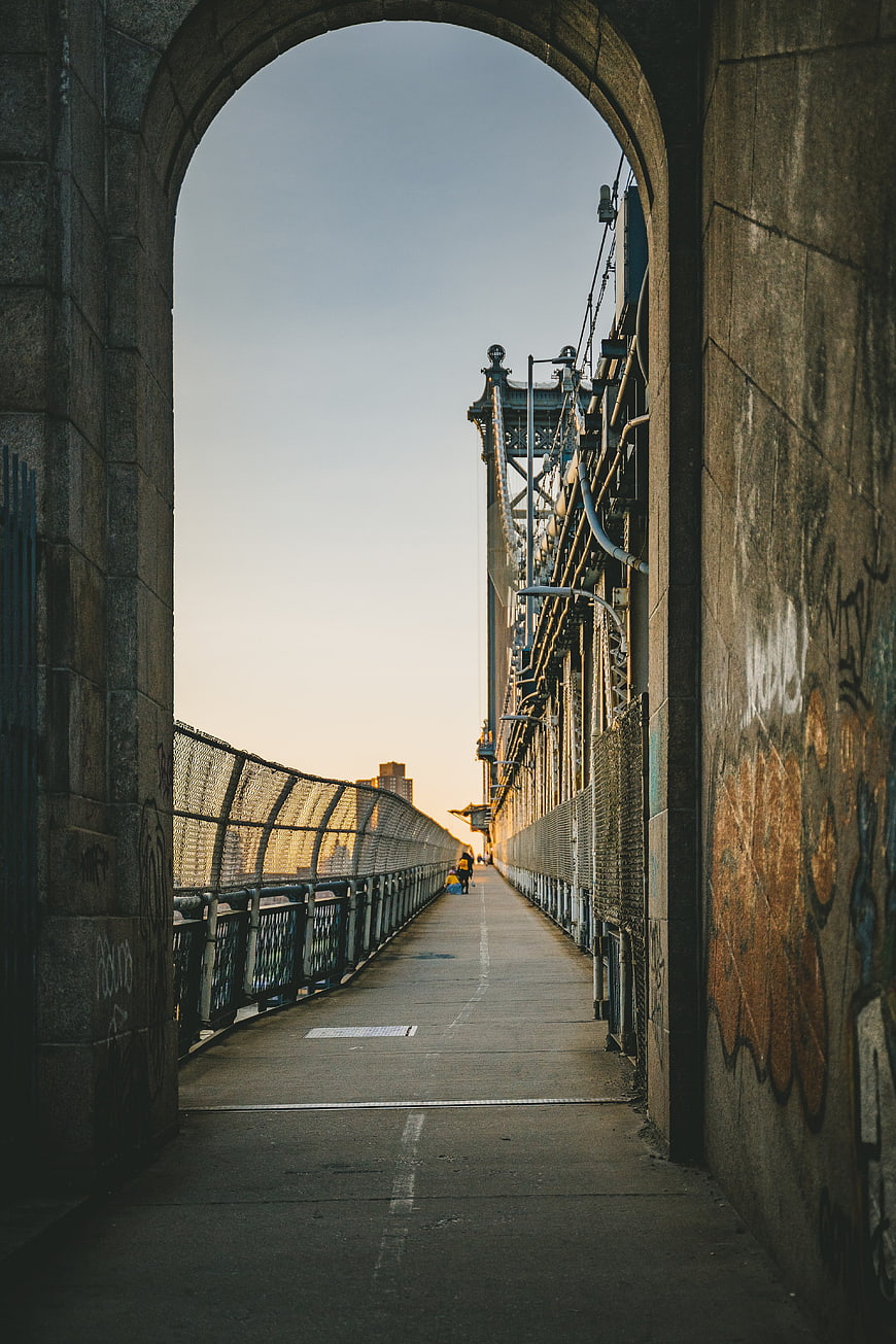 Man Walking on Manhattan Bridge Pathway at Sunset