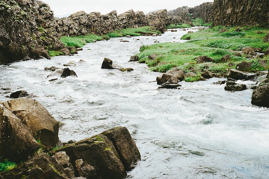 Rushing river flowing through rocky canyon with green banks