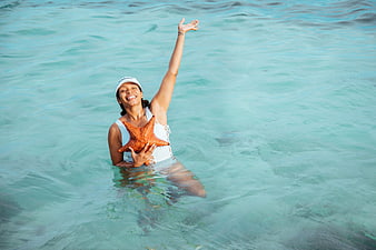 Smiling woman holding starfish in turquoise Caribbean sea