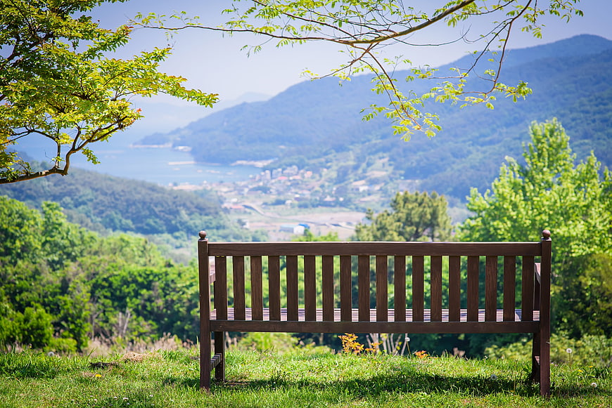 Empty wooden bench overlooking scenic mountain and ocean view