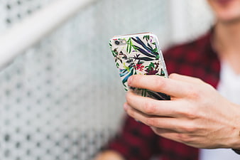 Close-up of hands holding smartphone with floral case