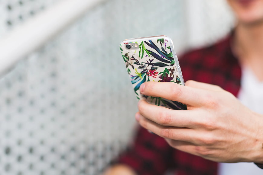 Close-up of hands holding smartphone with floral case