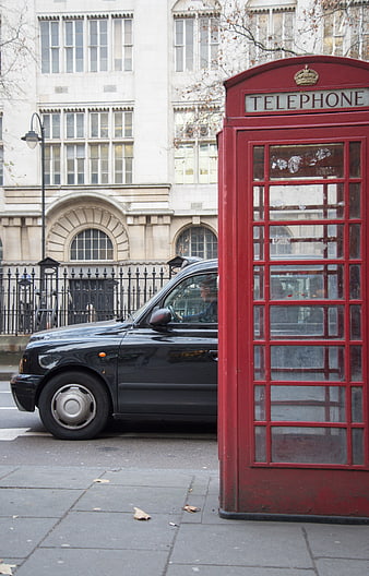 Classic red telephone box and black taxi cab on London street