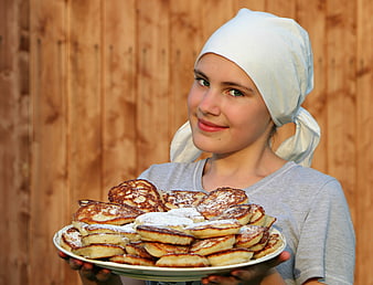 Young woman holding plate of homemade pancakes