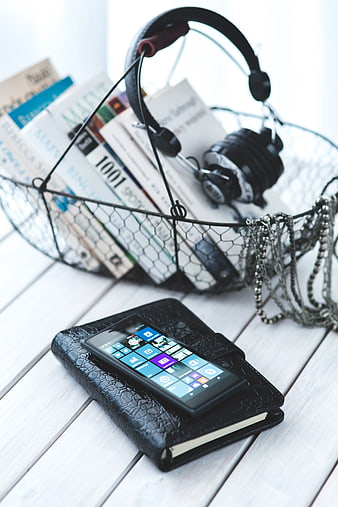 Smartphone on black notebook with headphones and books