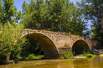 Old stone arch bridge over a river in summer