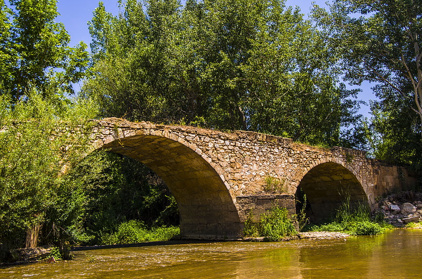 Old stone arch bridge over a river in summer