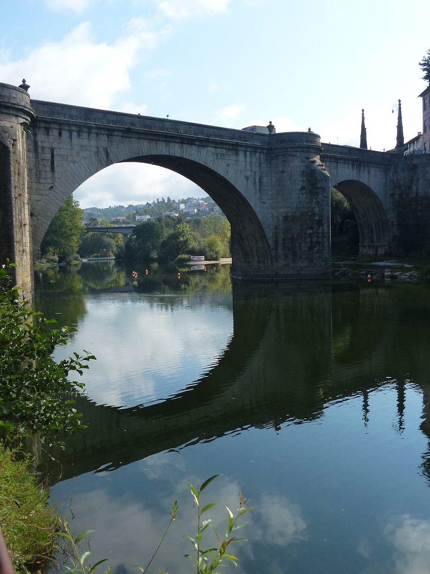 Historic stone bridge arch over calm river with reflection