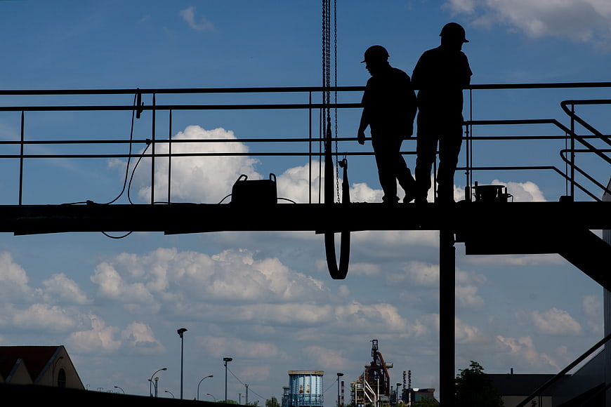 Silhouette of Two Construction Workers on Steel Beam