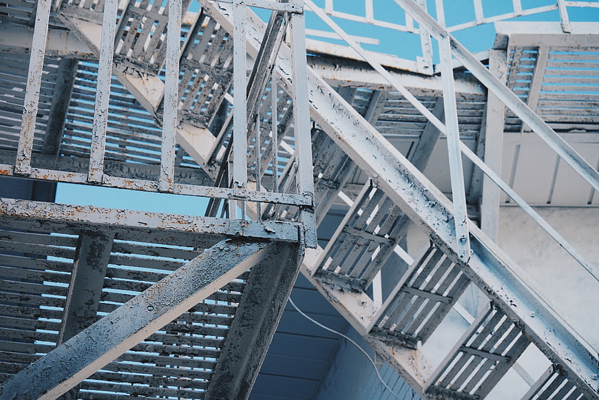 Low angle view of weathered white metal fire escape stairs