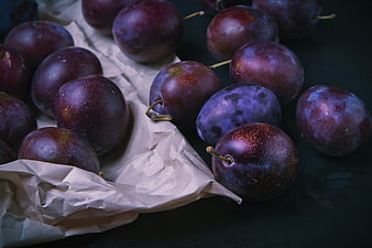 Fresh purple plums on crumpled paper dark background
