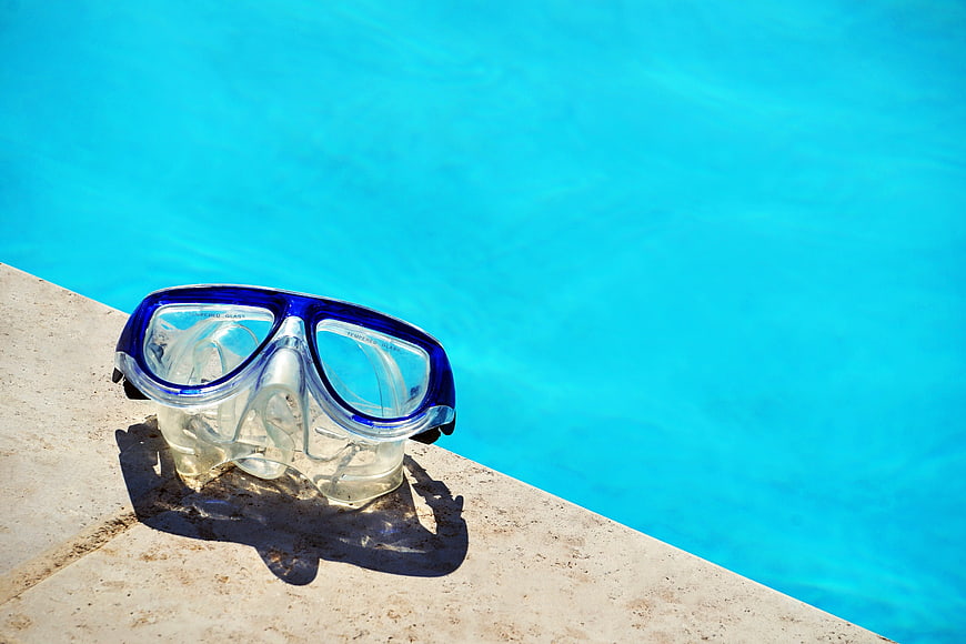 Blue Swimming Goggles on Poolside Edge