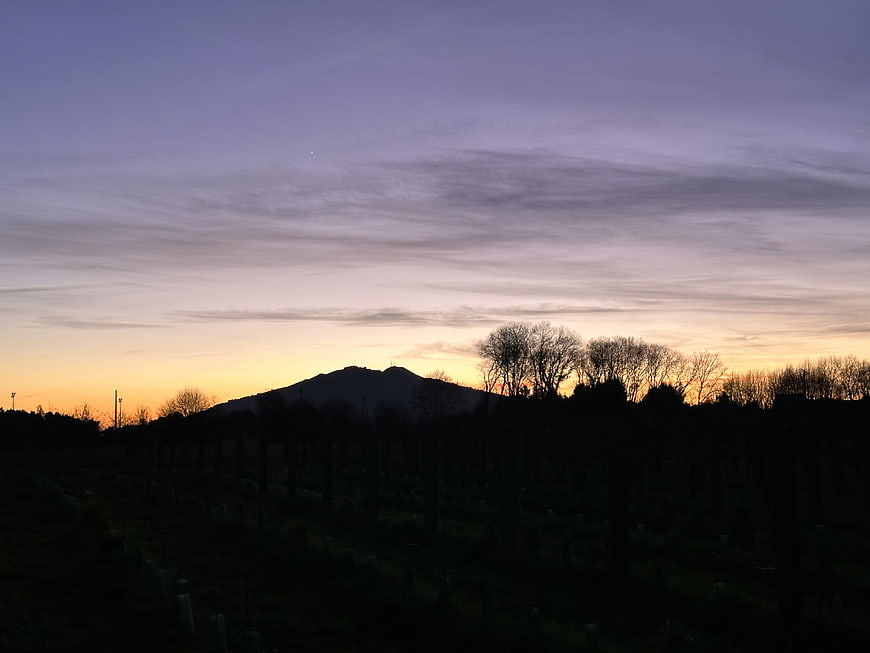 Silhouette of Mountain and Trees Against Purple and Orange Sunset Sky