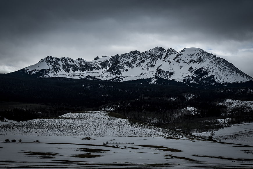 Dramatic Snow-Capped Mountain Range Under Stormy Sky