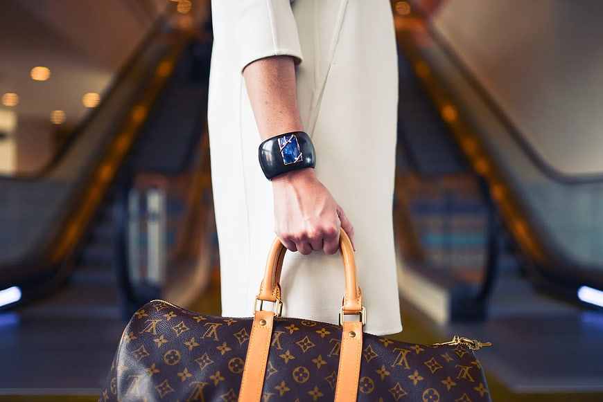 Woman Holding Luxury Louis Vuitton Handbag on Escalator