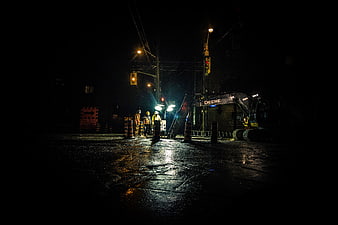 Nighttime road construction crew working on wet street