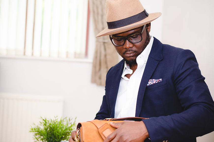 Stylish African American Man in Fedora and Suit Holding Leather Bag