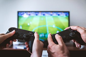 Two people playing soccer video game with controllers