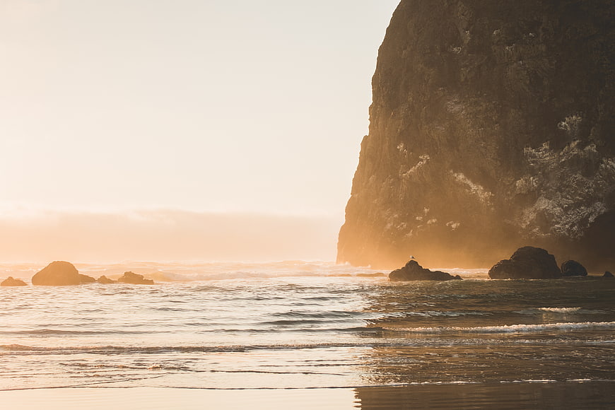 Golden Sunset Ocean Waves Crashing Against Rocky Cliff