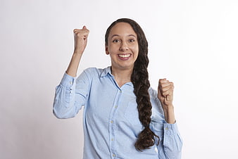 Excited woman celebrating success with raised fists in blue shirt