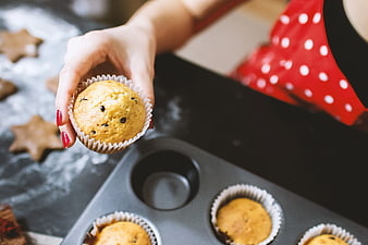Woman Holding Freshly Baked Muffin in Kitchen