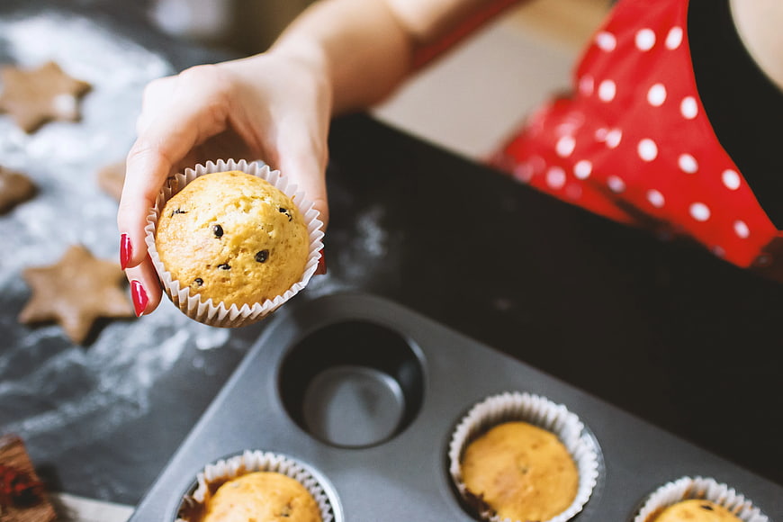 Woman Holding Freshly Baked Muffin in Kitchen