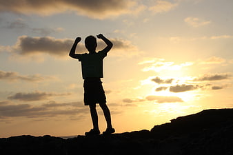 Silhouette of Boy Celebrating Victory at Sunset