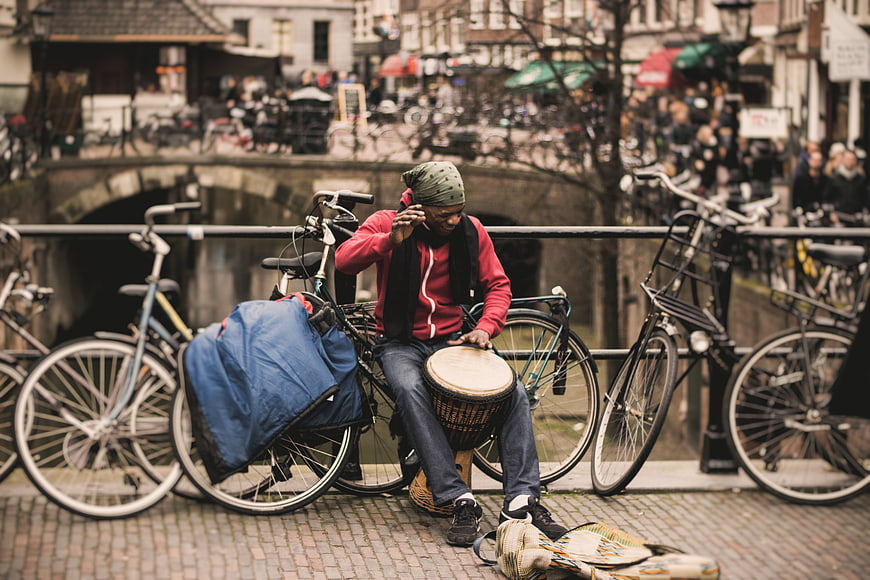 Man playing djembe drum on bicycle bridge in city