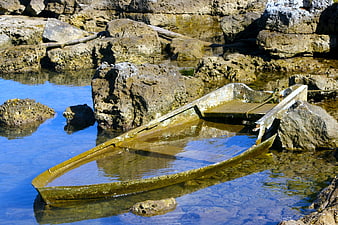 Old wooden boat stranded in rocky coastal tide pool