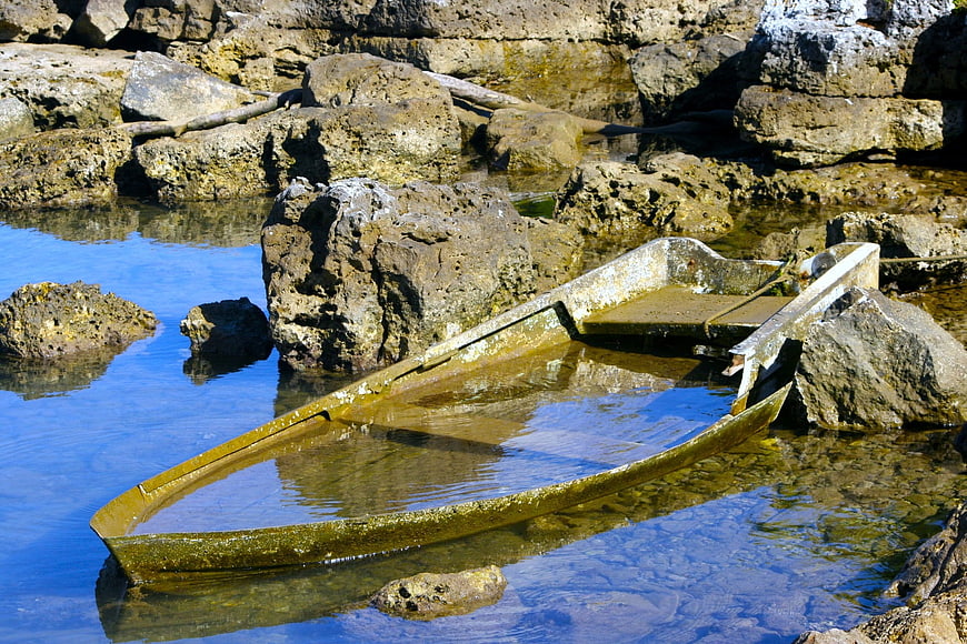 Old wooden boat stranded in rocky coastal tide pool
