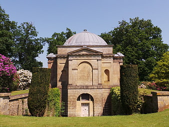 Classical stone mausoleum with dome in lush garden