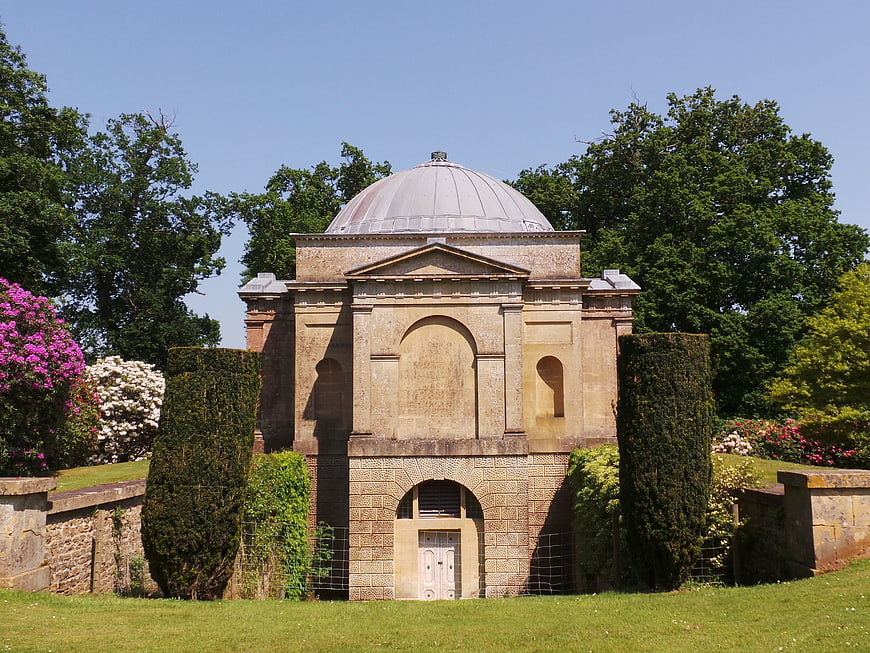 Classical stone mausoleum with dome in lush garden