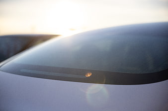 Close-up of white car windshield with sunset lens flare