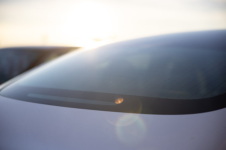 Close-up of white car windshield with sunset lens flare