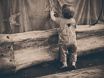 Toddler in denim overalls touching starfish on weathered wooden boat