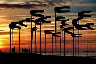 Silhouetted Wind Sculptures Against Vibrant Sunset Sky