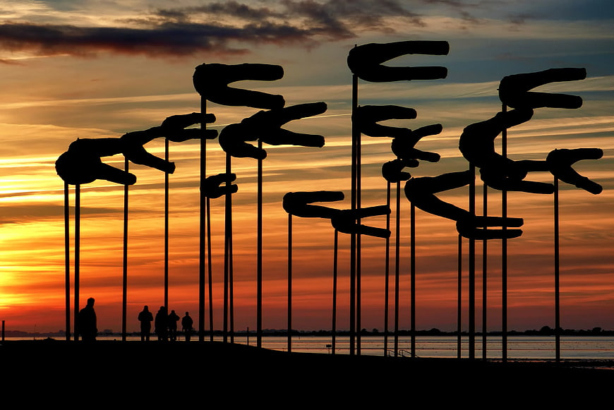 Silhouetted Wind Sculptures Against Vibrant Sunset Sky