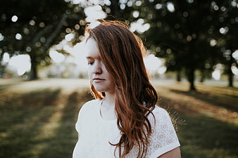 Pensive Young Woman with Red Hair in Park